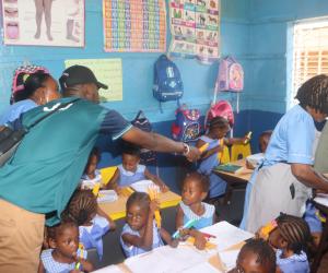 Joseph - a Develop Africa Sierra Leone staff - and teachers distributing coloring pens and pencils to kids in a classroom in Sierra Leone